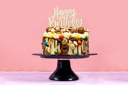 Foto de Pastel de capa de cumpleaños decorado con piezas de chocolate con texto feliz cumpleaños en tablero de madera - Imagen libre de derechos