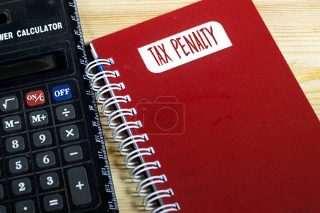 Word TAX PENALTY on red notebook with calculator. Finance concept
