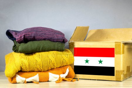 Photo for Carton box with used clothes for donation and Syria flag Earthquake, catastrophe volunteering - Royalty Free Image