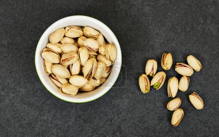 Photo for Pistachios in bowl on grunge gray and black background - Royalty Free Image