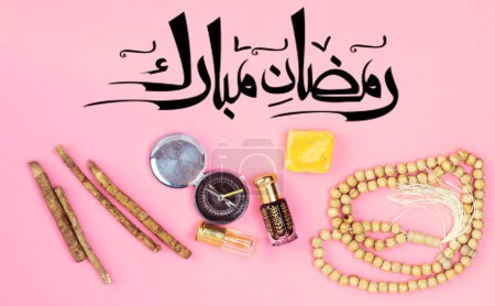 Foto de Arabic calligraphy meaning happy ramadan in english,  rosary, siwak and perfume on pink background - Imagen libre de derechos