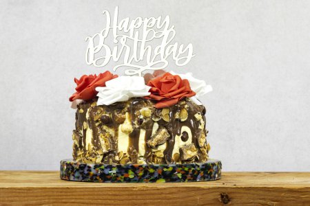 Foto de Pastel de capa de cumpleaños decorado con piezas de chocolate con texto feliz cumpleaños en el podio de mármol en el tablero de madera - Imagen libre de derechos