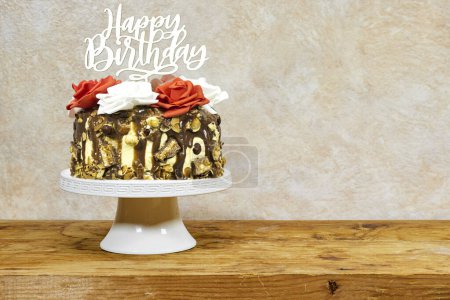 Foto de Pastel de capa de cumpleaños decorado con piezas de chocolate con texto feliz cumpleaños en soporte de pastel en tablero de madera - Imagen libre de derechos