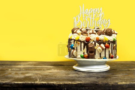 Foto de Pastel de capa de cumpleaños decorado con piezas de chocolate con texto de feliz cumpleaños en el pastel de pie en el tablero de madera - Imagen libre de derechos
