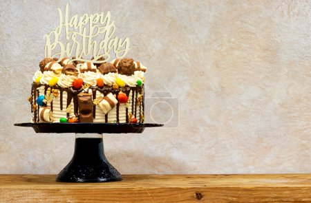 Foto de Pastel de capa de cumpleaños decorado con piezas de chocolate con texto de feliz cumpleaños en el pastel de pie en el tablero de madera - Imagen libre de derechos