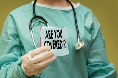 Téléchargez les photos : Médecin chirurgien tenant une carte papier avec êtes-vous couvert ? concept - en image libre de droit