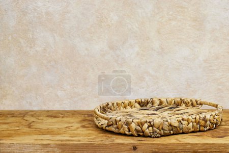 Photo for Empty Esparto halfah plate on wooden table with modern tablecloth. Kitchen mock up for design and product display - Royalty Free Image