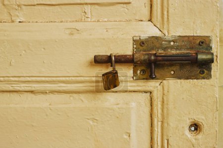 Foto de Viejo pestillo de cerradura de metal en la puerta sucia amarilla con candado - Imagen libre de derechos