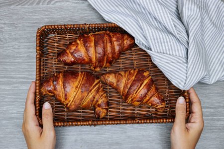 Photo for Closeup hands holding a esparto halfah basket with Fresh croissants - Royalty Free Image