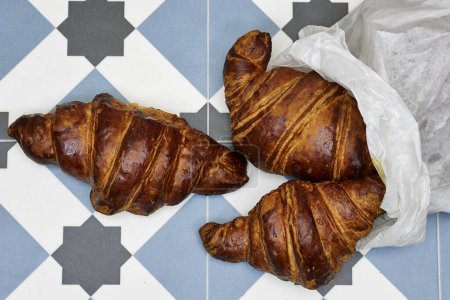 Photo for Fresh croissants in paper bag on tiles floor - Royalty Free Image