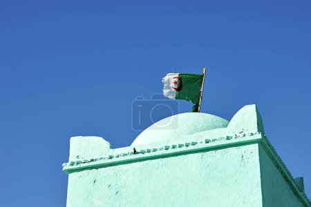 Algeria national flag cloth fabric waving on the sky on old historic mausoleum 