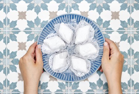 las manos de la placa con galletas tradicionales de Argelia llamado makrout es una pasta de almendras formando forma de diamante y cubierto con azúcar en polvo