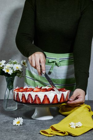 woman hold a knife and cut a strawberry cake or Fraisier in french language on black plate
