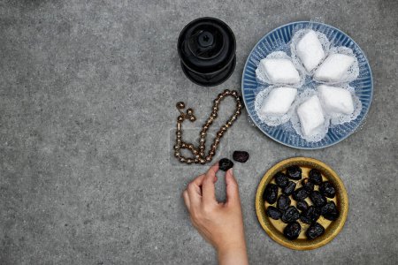 eid al fitr oder aldha, ramadan concept iftar und breakfast. Makrout-Algeria-Kekse aus Mandelpaste und mit Puderzucker bedeckt, Hand halten Ajwa-Datteln, Laterne und Rosenkranz-Perlen