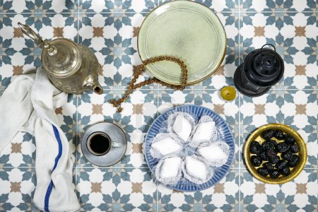 eid al fitr oder aldha, ramadan concept iftar und breakfast. Frauen trinken Kaffee und essen Makrout-Algeria-Kekse aus Mandelpaste, die mit Puderzucker, Datteln, Laterne bedeckt sind