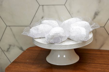 algerian traditional cookies named makrout is a almond paste forming diamond shape and covered with icing sugar in stand cake plate