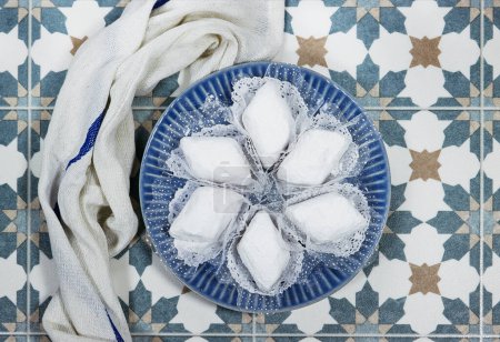 galletas tradicionales de Argelia llamado makrout es una pasta de almendras formando forma de diamante y cubierto con azúcar glaseado sobre fondo de azulejos árabes