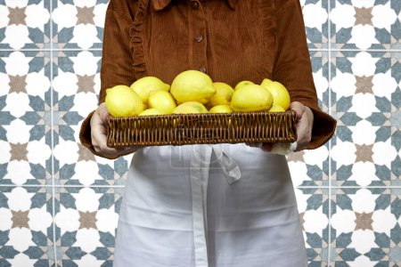 Mujer sosteniendo media cesta llena de limones, concepto de jardinería, publicidad de limonada