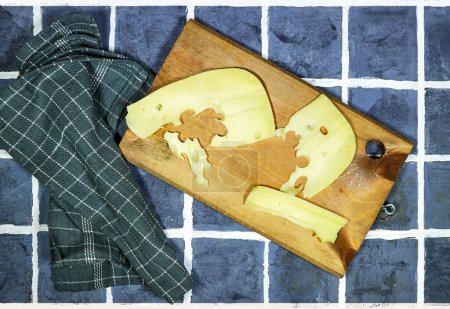 rebanada de queso Gruyere en tabla de cortar de madera en baldosas piso
