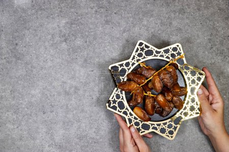 happy ramadan or eid concept, deglet nour algeria dates in stars plate, hands holding one piece