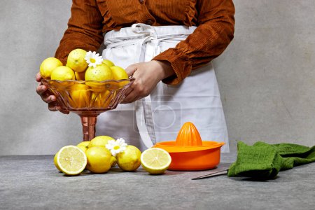 photo de style de vie de la femme tenant un bol de citron jaune frais
