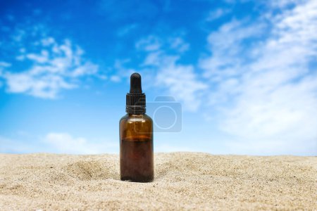 Blank amber glass essential oil bottle with pipette on sand. Skin care concept with natural cosmetics