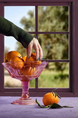 hand hold Fresh ripe mandarine in stand plate near window