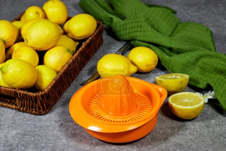 halfah cesta llena de limones sobre mesa de madera con exprimidor de plástico, concepto de jardinería, limonada