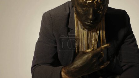 Concepto de arte moderno, hombre con máscara dorada en la cara. Creativo. Misterioso hombre de incógnito en chaqueta con maquillaje y elementos de oro en su cara