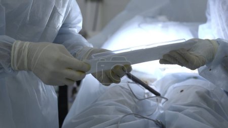 Krankenschwester reicht steriles Einweg-Set an einen Arzt im Operationssaal. Handeln. Konzept der Gesundheitsfürsorge und Medizin