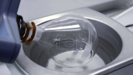 Nahaufnahme des Mechanismus, der die saubere Glasflasche dreht. Archivmaterial. Medizinische oder chemische Laborgeräte
