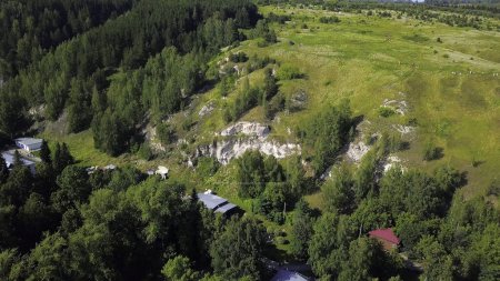Vista aérea de un acantilado de roca y pinos. Clip. Volando sobre prados verdes y formaciones de piedra