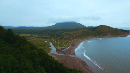 Top view of amazing landscape of mountain coast on cloudy day. Clip. Cinematic landscape of coast with rocky green mountains. Beautiful sea off coast of mountainous north island.