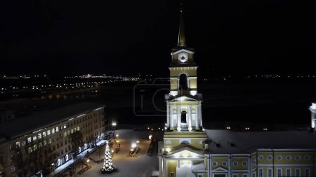 Aerial view of the illuminated church and residential buildings. Clip. Beautiful city at night