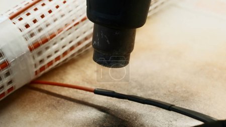 Téléchargez les photos : Maître électricien chauffage isolation autour des fils de cuivre avec un outil spécial. Créatif. Détails de l'atelier et équipement - en image libre de droit