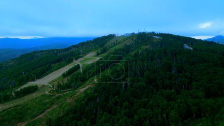 Aerial view of cable cars in mountains. Clip. Travel and outdoor activities, hills, coniferous trees and blue sky