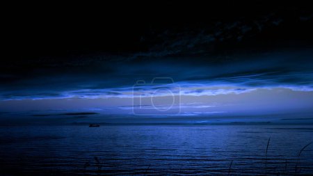 Fairytale breathtaking night landscape of rippling river with a floating boat. Clip. Dark blue sky and moon shine, heavy clouds above water