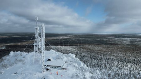 Frozen repeater antenna on the top of a hill in winter. Clip. Aerial view of winter valley panorama and blue cloudy sky