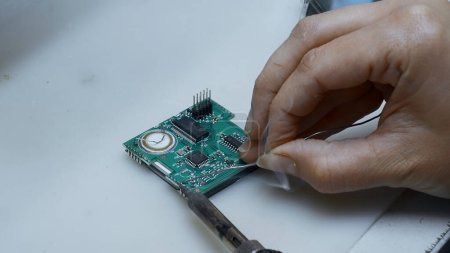 Großaufnahme von Ingenieur tut Computer Motherboard Löten. Kreativ. Akribische Arbeit beim Löten eines Chips