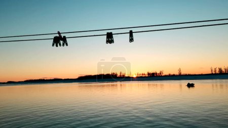 Beautiful sunset and blue sky over a forest lake at evening. Clip. Gentle lake ripples and ropes with clothespins