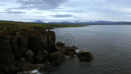Bird eye view of calm ocean and stone rock cliffs at Oregon coast. Clip. Aerial of the ocean water surface and green meadows