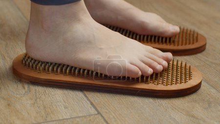 Foto de Pies femeninos de pie sobre tablas con clavos, de cerca. Medios. Descalza hembra parada sobre tabla de clavos de yoga - Imagen libre de derechos