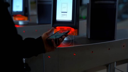 Close-up of passing through electronic turnstile with barcode scanner. Media. Using smartphone to get access inside the building
