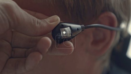 Close-up of flashing earphone. Stock. Man uses special earphone with backlight. Man with earpiece for hearing or wiretapping.