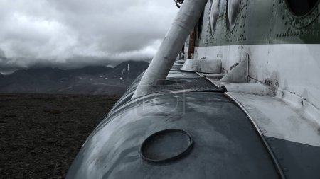 Close up of old rusty airplane on a hill top. Clip. Aircraft exterior details with heavy clouds and mountains on the background