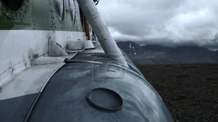 Close up of old rusty airplane on a hill top. Clip. Aircraft exterior details with heavy clouds and mountains on the background