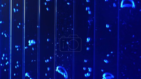 Nahaufnahme von Unterwasseraufnahmen von Luftblasen in farbiger flüssiger Substanz. Clip. Vertikale Blasen fließen im Wasser