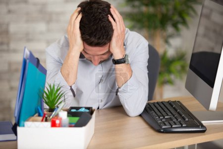 upset fired office worker in modern office with carton box