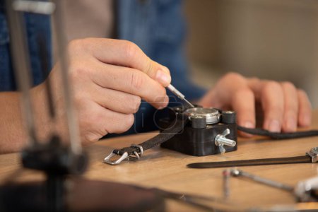 close-up of man repairing wrist watch at desk in workshop