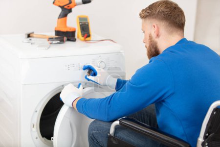 man in wheelchair repairs a tumble dryer